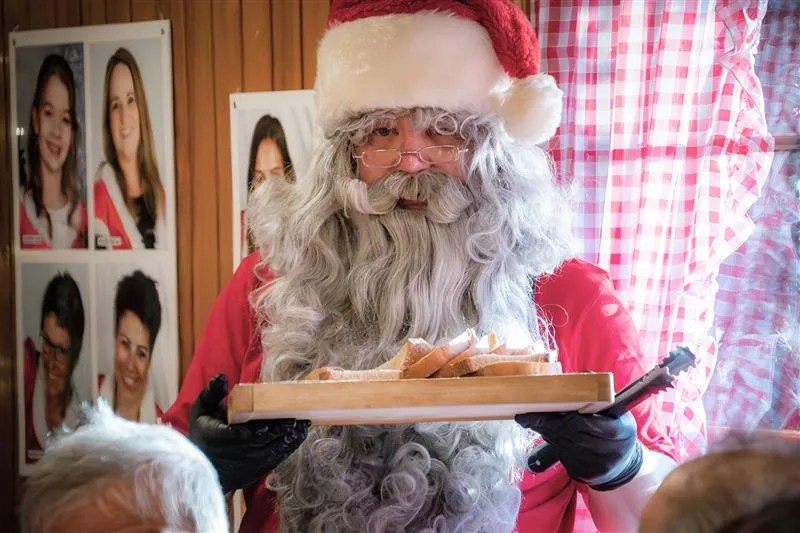 Ein Samichlaus verteilt Würstchen und Brot.